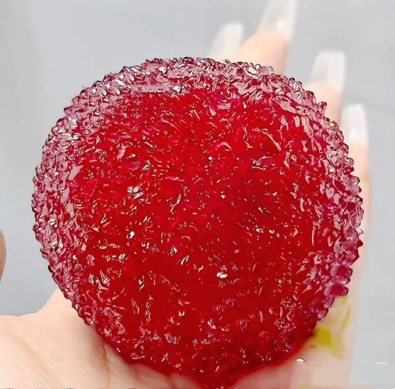Red gelatinous ball Squishy held between fingers against a neutral background