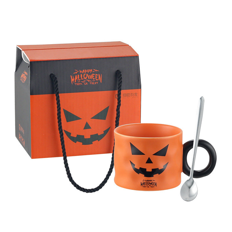 Halloween-themed mug with black handle and pumpkin face design, accompanied by a matching gift bag.
