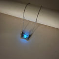 Necklace with a glowing blue pendant on a white surface