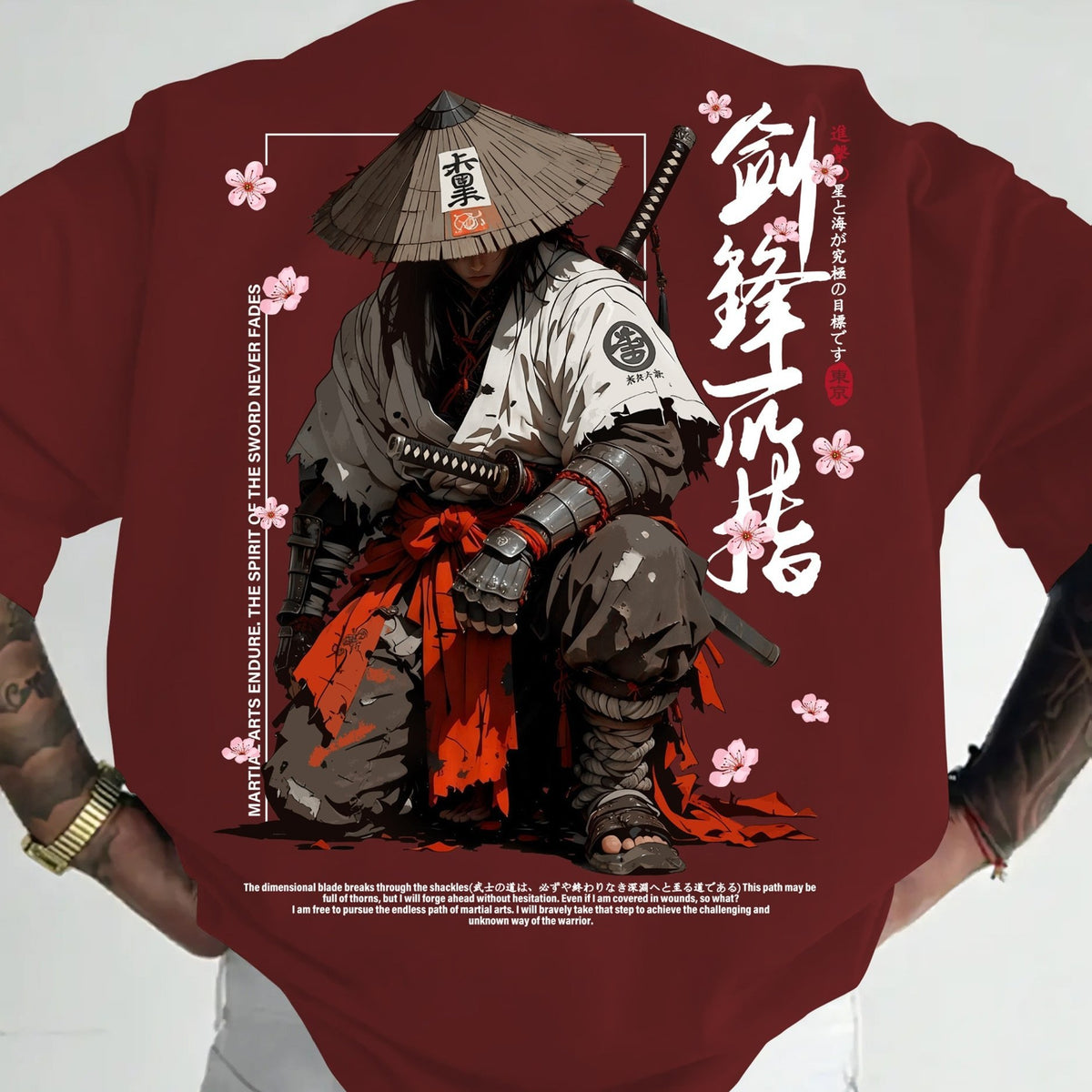 A person wearing a dark red short-sleeve T-shirt with a large anime-style samurai graphic on the front. The design features a samurai in a conical hat, white and gray armor, an orange-red sash, and white Japanese calligraphy with pink cherry blossoms.