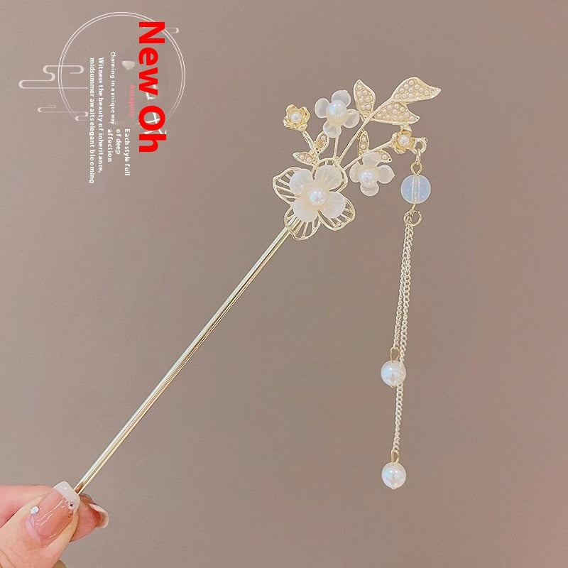 Decorative hair stick with floral design held by a hand against a brown background