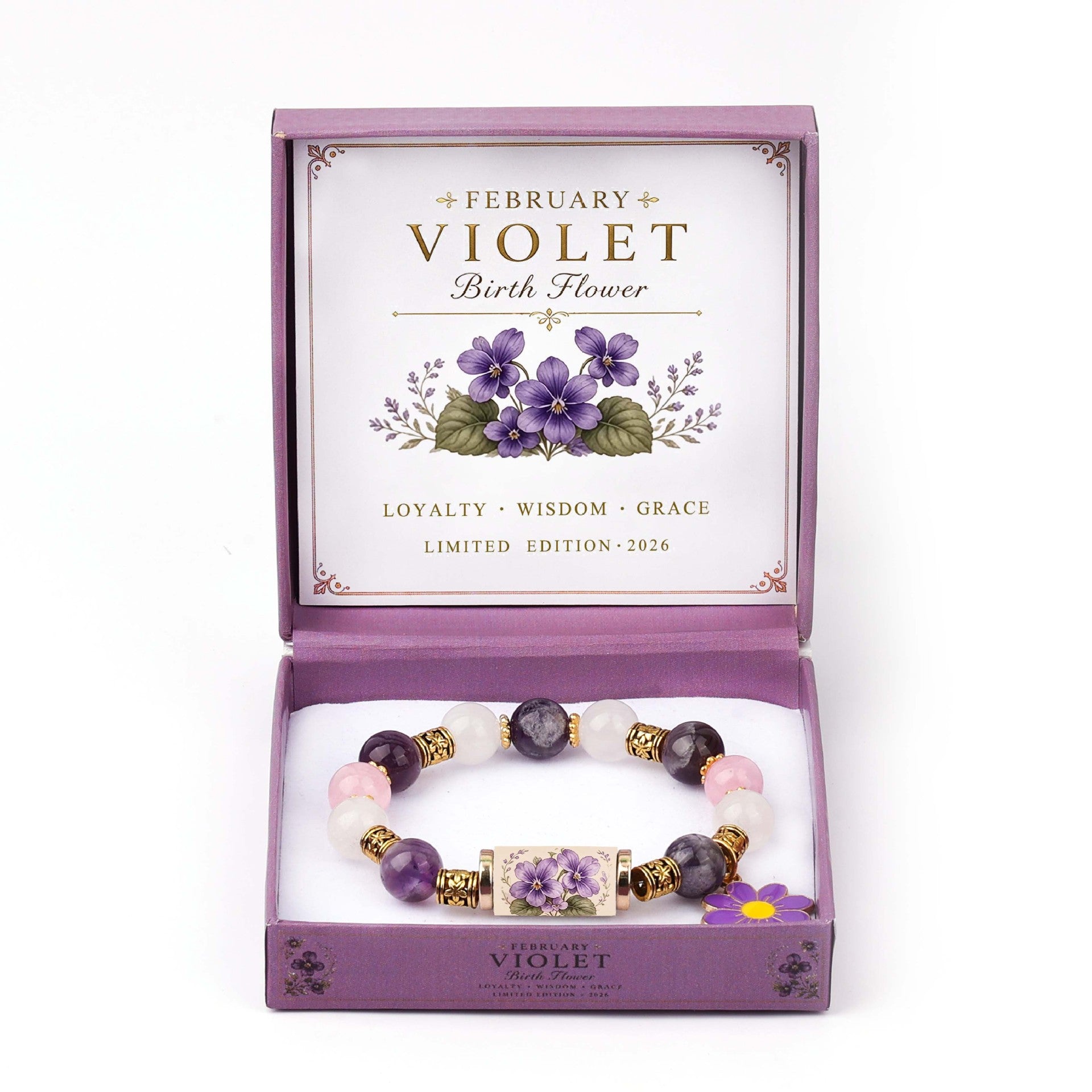 A beaded bracelet with purple, white, and pink gemstones and gold-toned accents, displayed inside an open lavender gift box labeled 'February Violet Birth Flower' with floral artwork and the words 'Loyalty • Wisdom • Grace' and 'Limited Edition 2026.'.