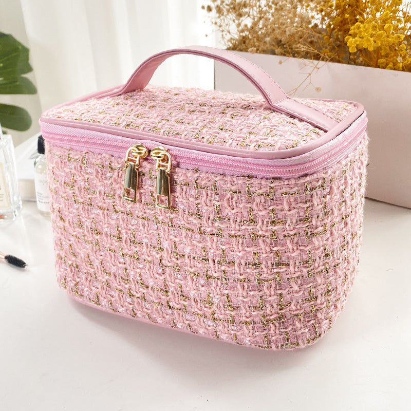 Pink textured cosmetic bag with gold accents on a white surface.