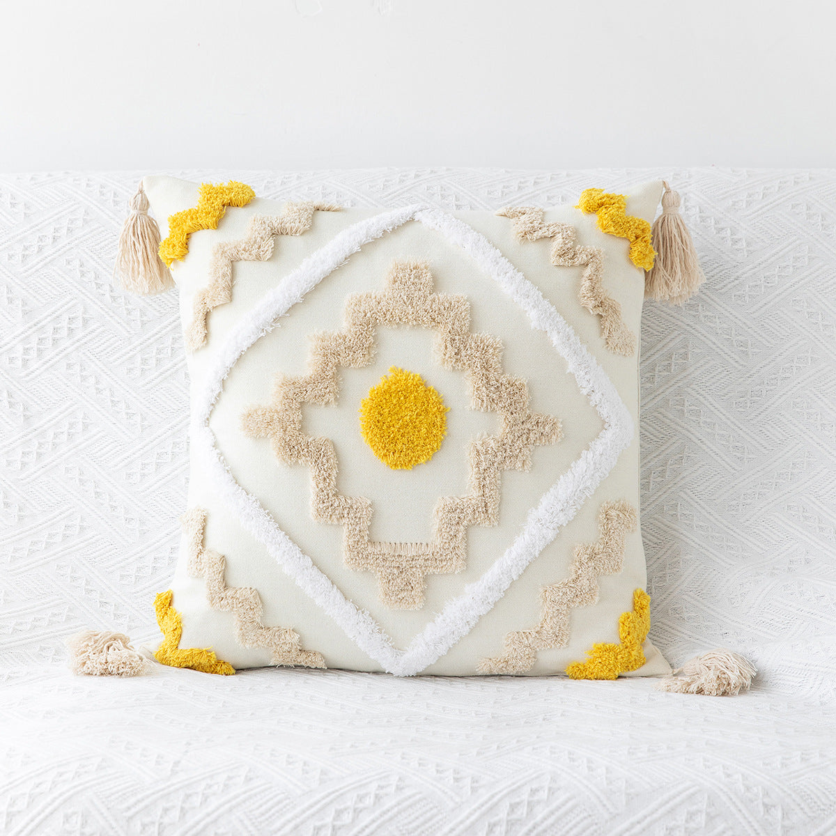 Decorative pillow with geometric pattern and tassels on a textured white background