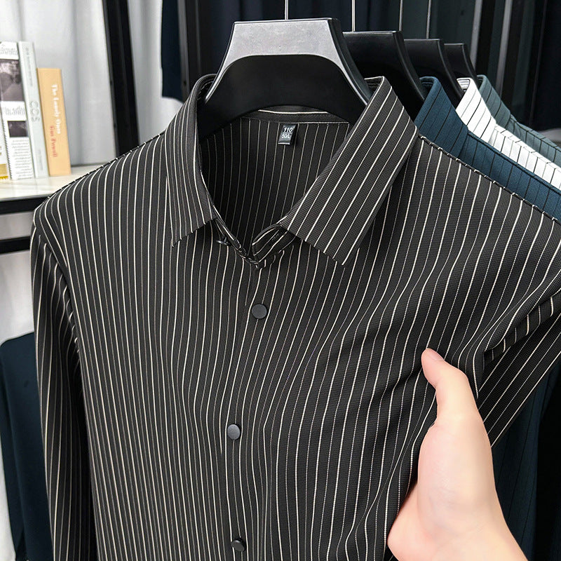 Black and white striped shirt on a hanger with a hand holding it, against a blurred indoor background.