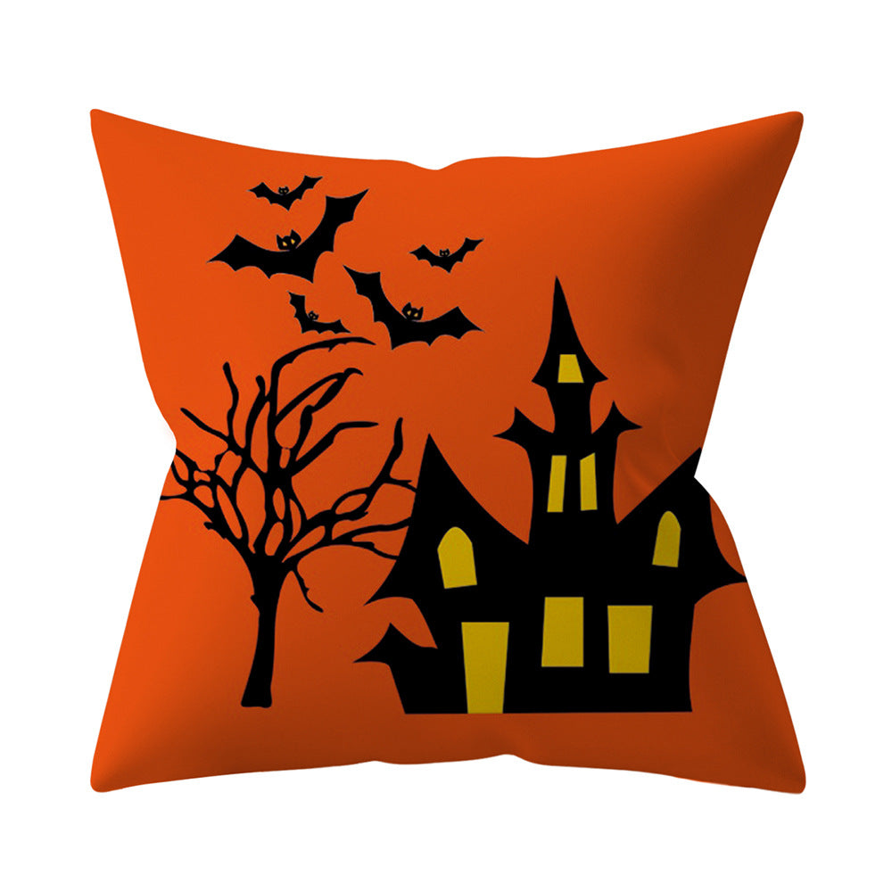 Halloween-themed pillow with a haunted house, tree, and bats on an orange background.
