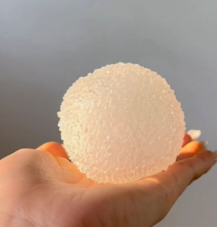 Hand holding a textured white ball Squishy against a plain background
