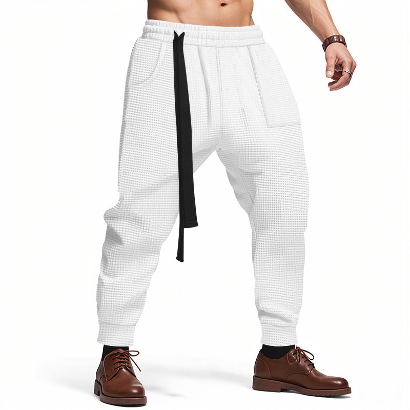 White checkered pants with a black strap worn by a person on a white background