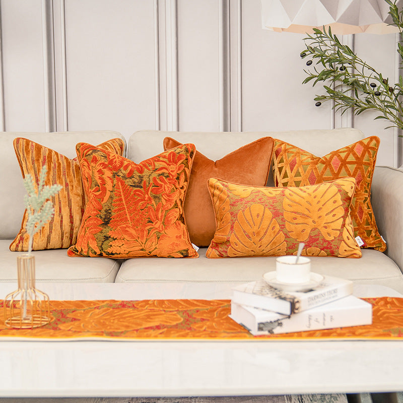 Decorative pillows and table runner on a sofa with a neutral background