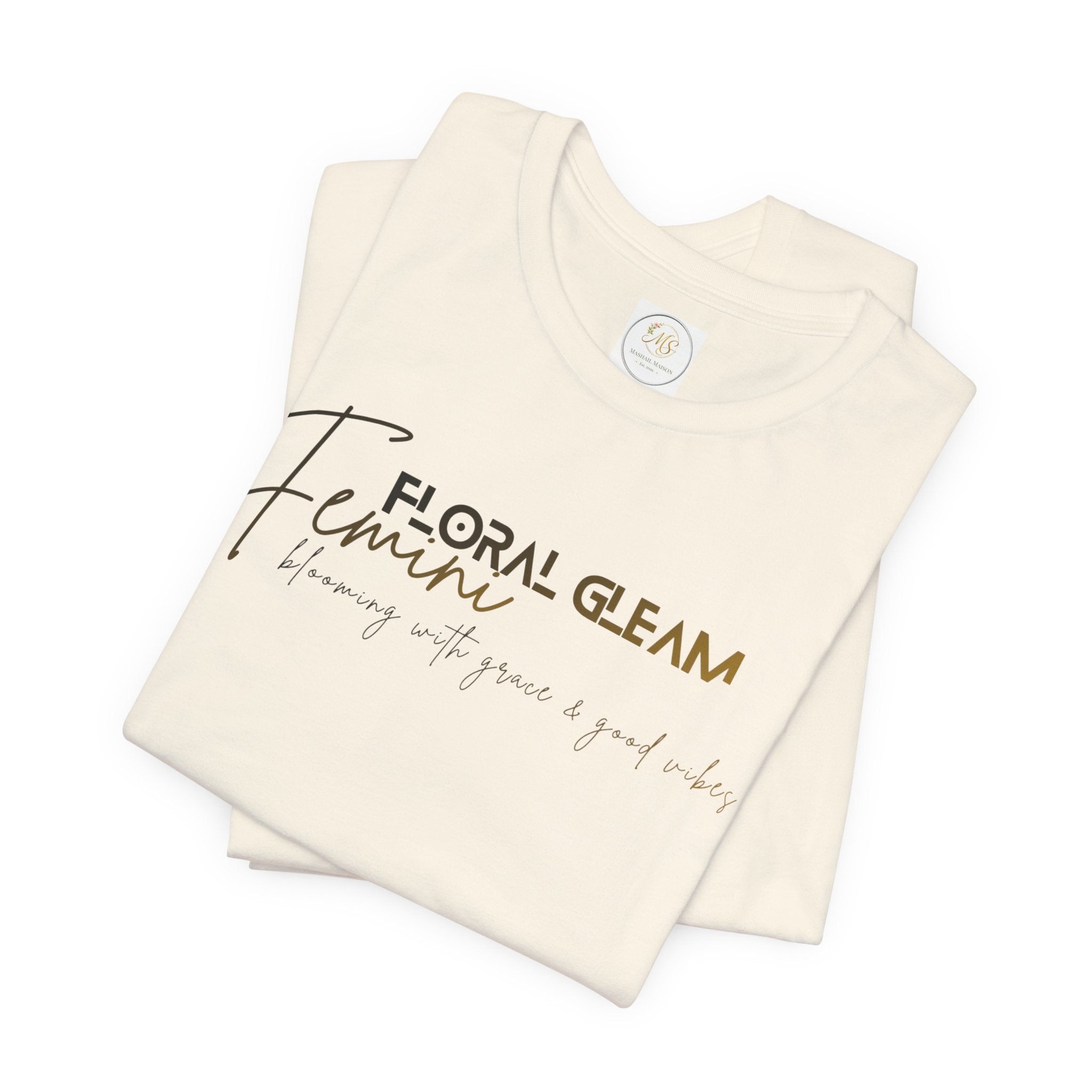 Folded cream-colored t-shirt with 'Floral Gleam' text on a white background