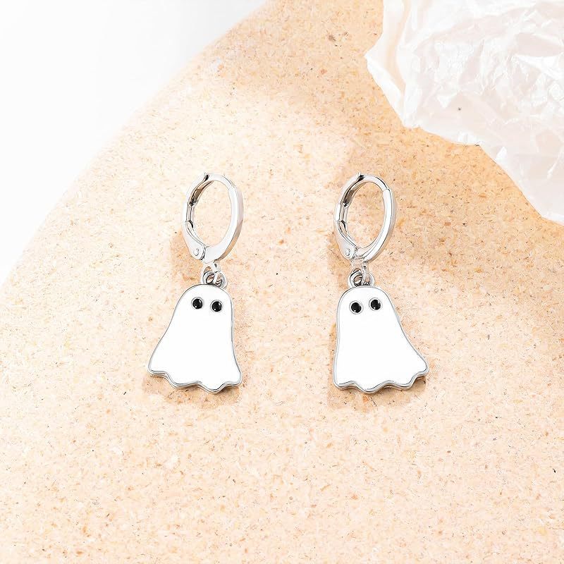 Ghost-shaped earrings on a sandy surface