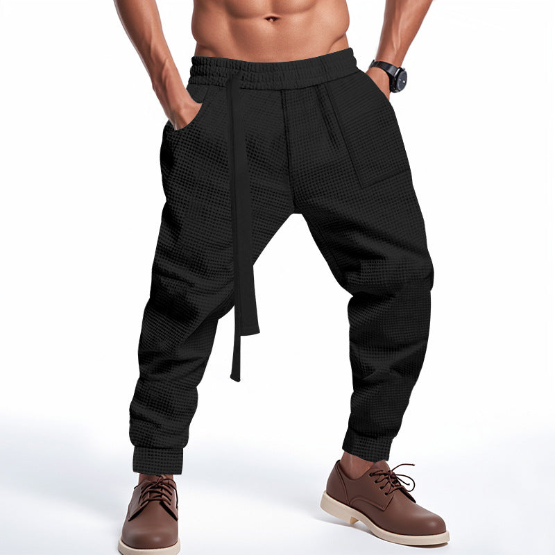 Black textured pants worn by a person on a white background