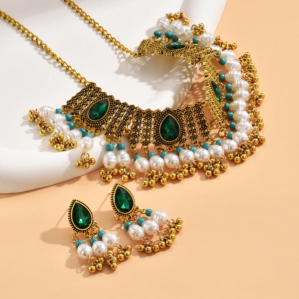 Ornate gold, green, and pearl jewelry set on a beige background