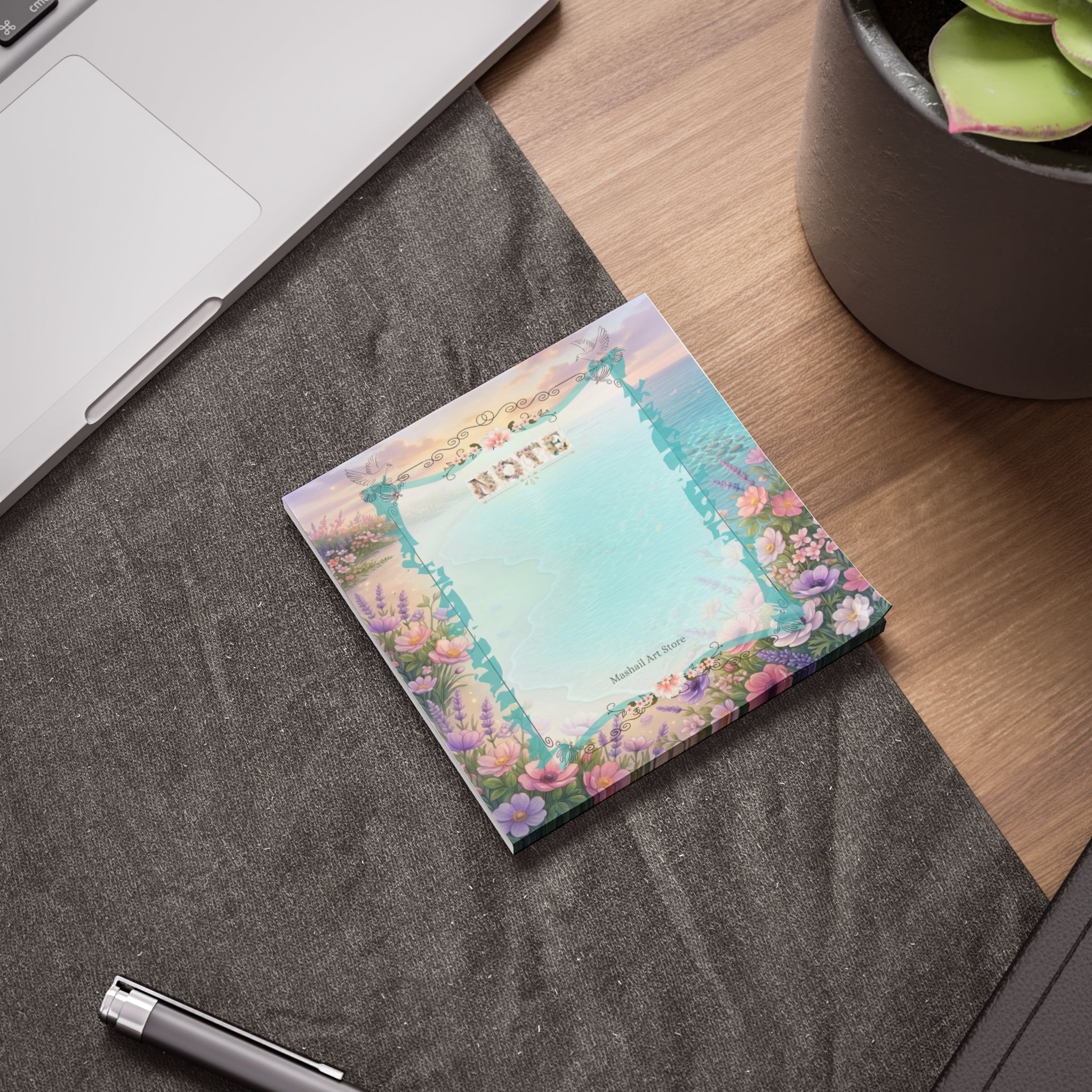 Decorative notepad with floral design on a desk next to a laptop and pen