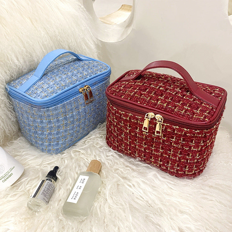 Two cosmetic bags, one blue and one red, on a fluffy white surface with skincare products in front.