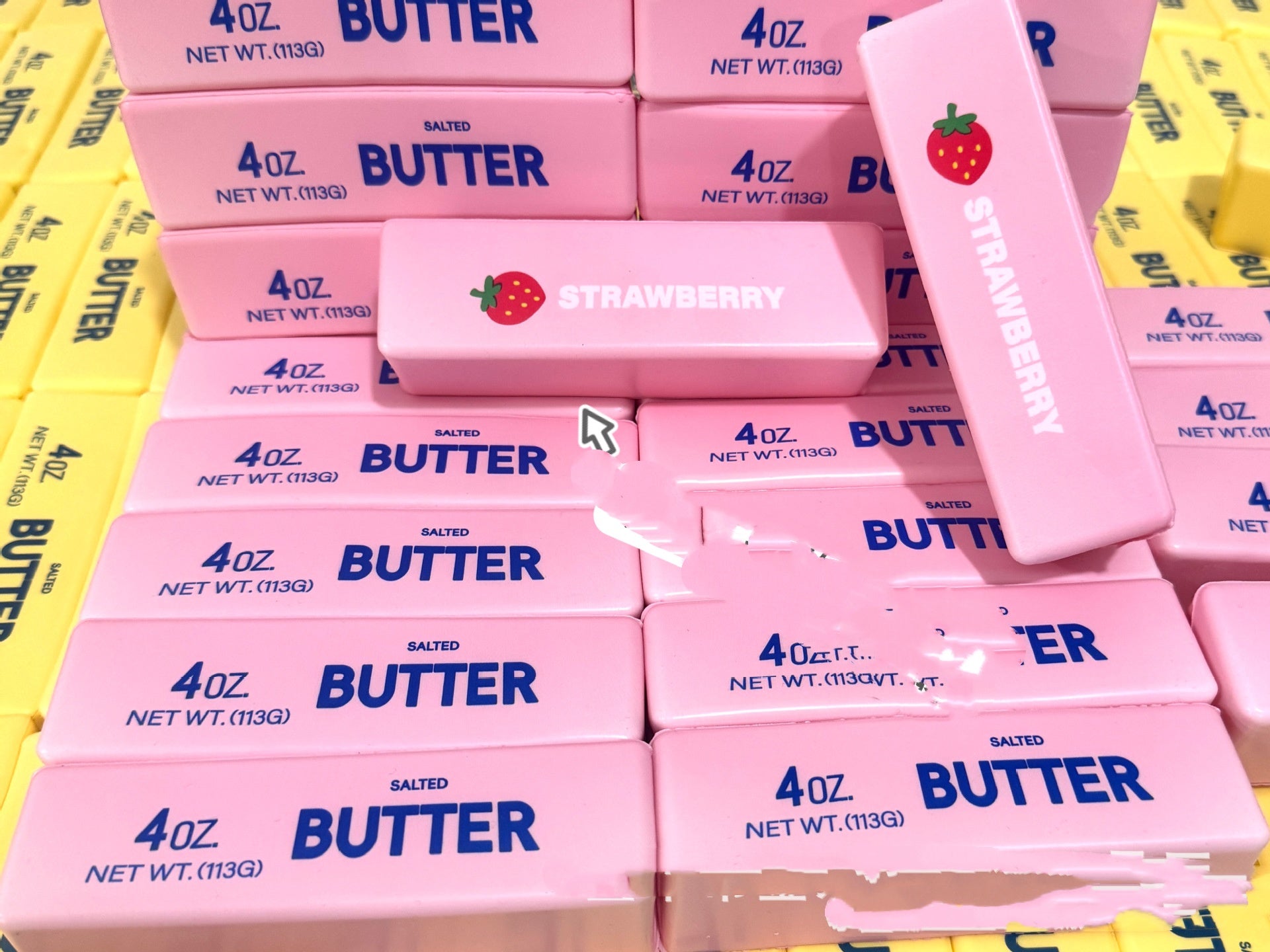 Pink and blue butter squishy packaging with strawberry flavor label on a yellow background
