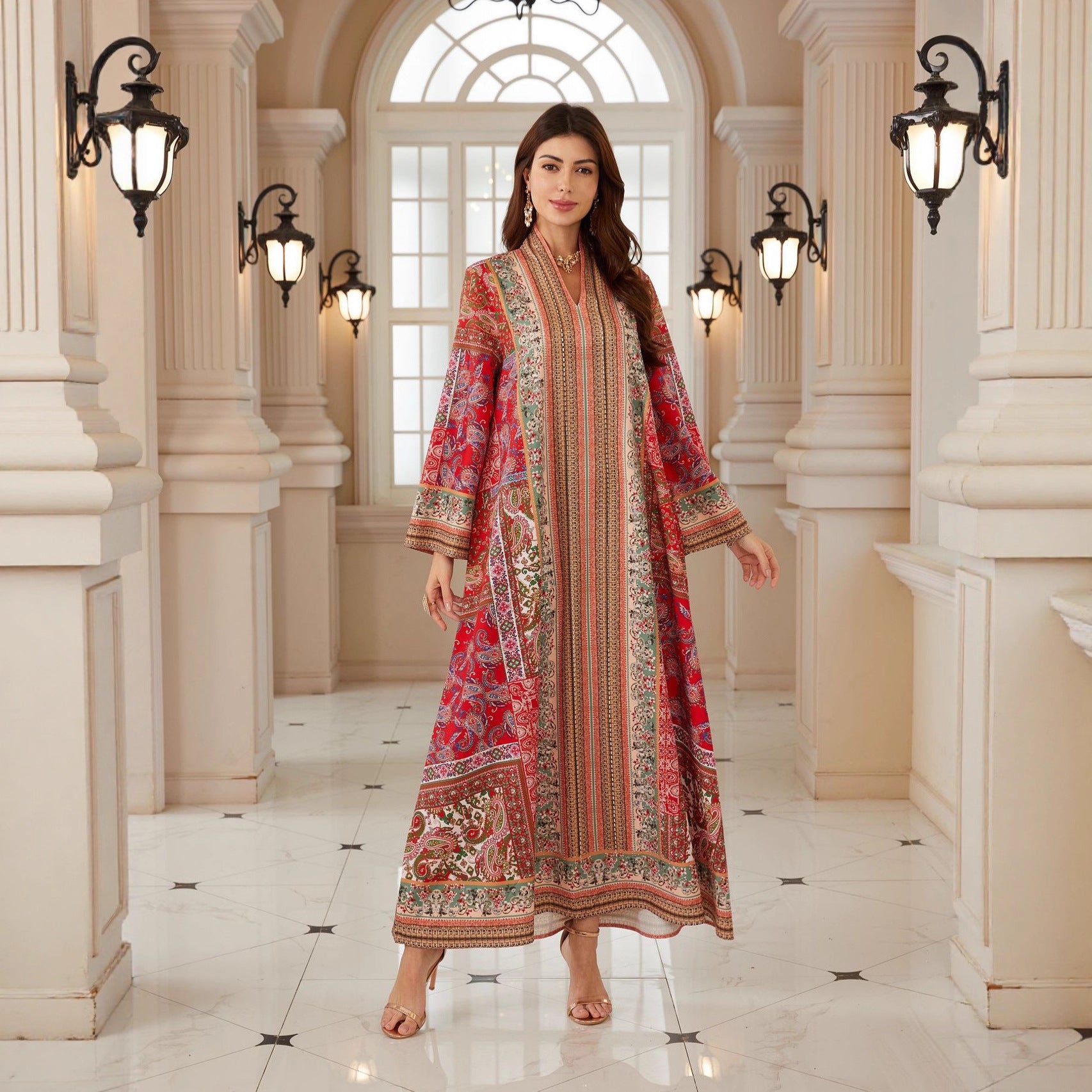 Woman in a patterned dress standing in an elegant hallway with columns and lights.