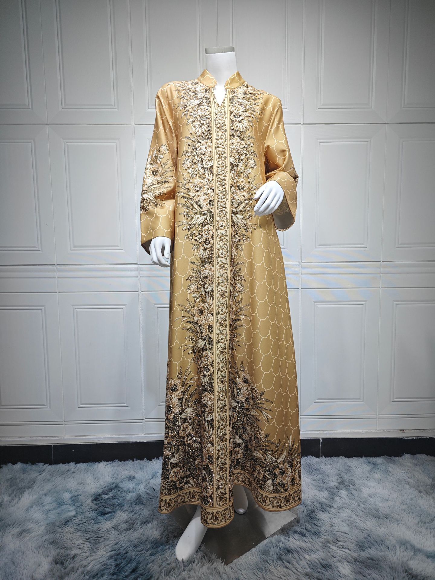 Gold embroidered dress on a mannequin against a white paneled wall.