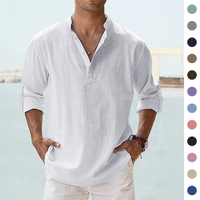 A man wearing a white long-sleeve linen henley shirt with rolled-up sleeves and white pants, standing outdoors near a light blue water background. A vertical row of color swatches appears on the right side of the image.