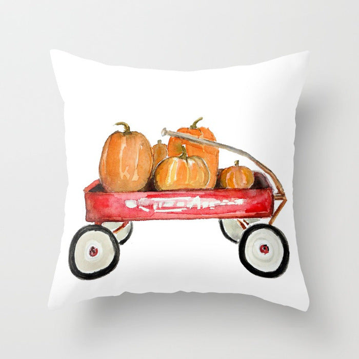 Decorative pillow with a red wagon and pumpkins design on a white background