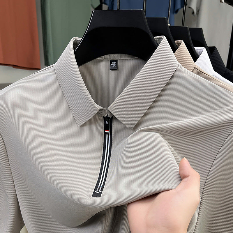 Light gray shirt with a zipper held by a hand on a blurred clothing rack background