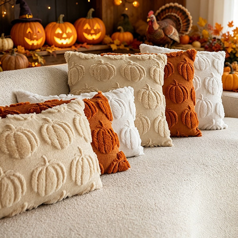 Four decorative throw pillows with raised pumpkin textures arranged on a light beige sofa in a cozy autumn setting. The pillows come in cream, white, and rust-orange colors, with a warm, festive background featuring jack-o'-lanterns and a turkey decoration.
