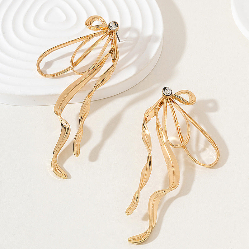 Gold earrings with a bow design on a light background