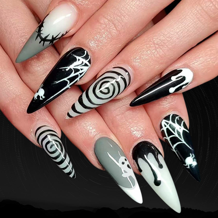 Halloween-themed nail art with black, white, and gray designs on a hand.