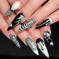 Halloween-themed nail art with black, white, and gray designs on a hand.
