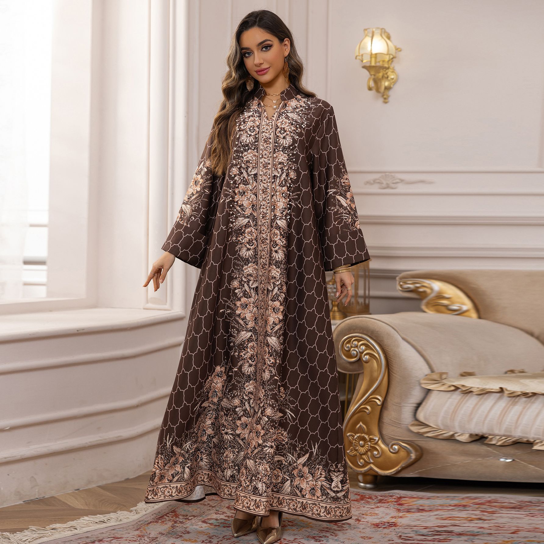 Woman in a long, patterned dress standing in an elegant room with decorative elements.