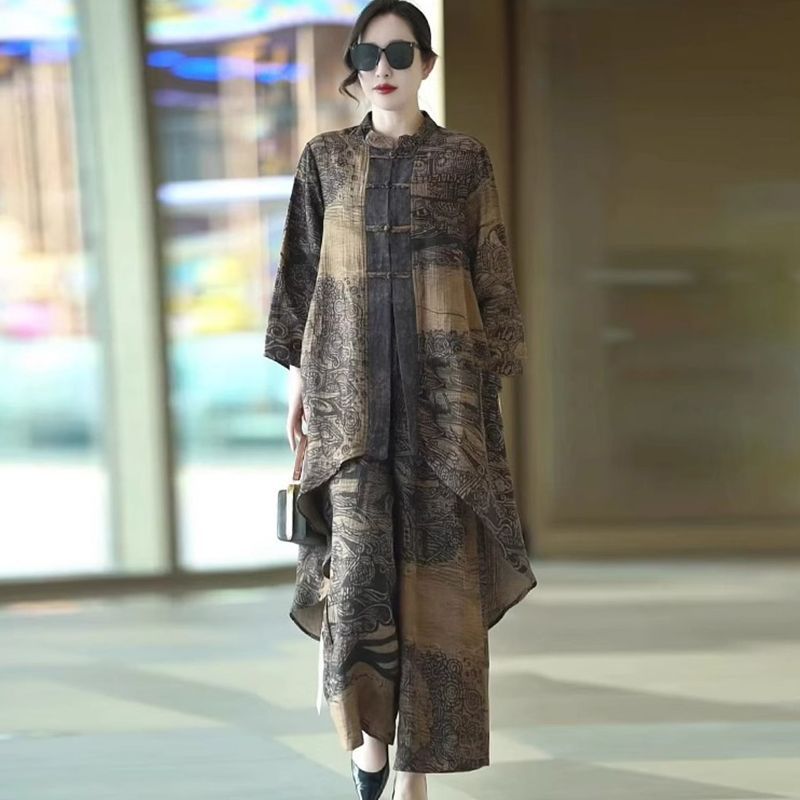 A woman models a matching two-piece outfit featuring a long-sleeve button-up jacket and wide-leg trousers in a brown and black patchwork print, set against a blurred indoor background.