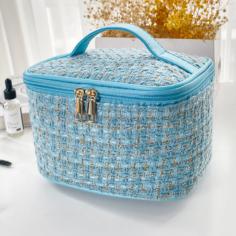 Blue textured cosmetic bag with gold accents on a white surface.