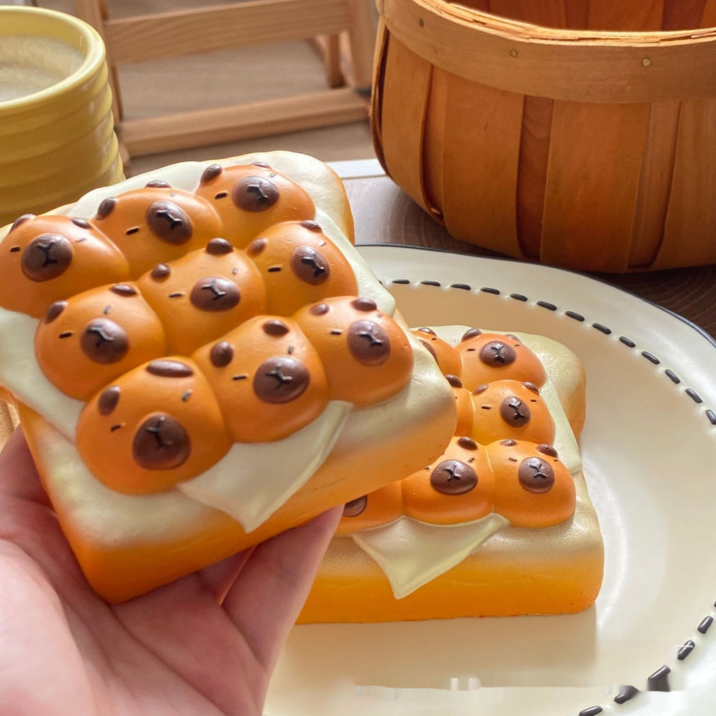 Bread with cartoonish animal faces on a plate, held by a hand.