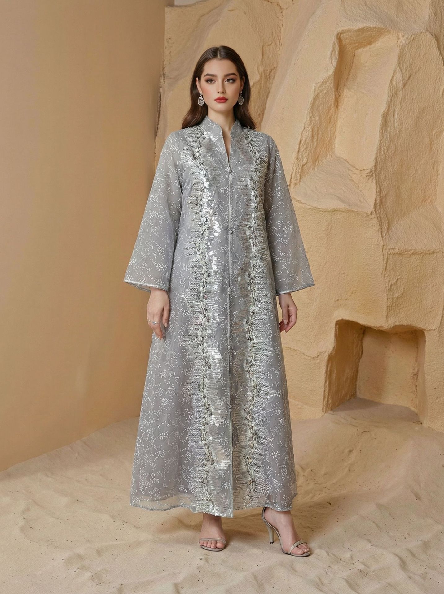 Woman wearing a silver sequin dress against a beige stone wall.