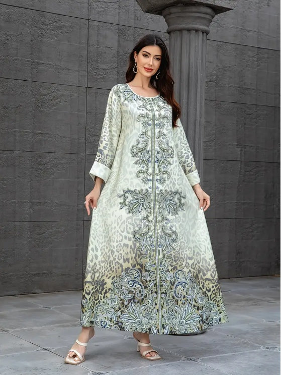 Woman wearing a long, patterned dress standing against a gray stone wall.
