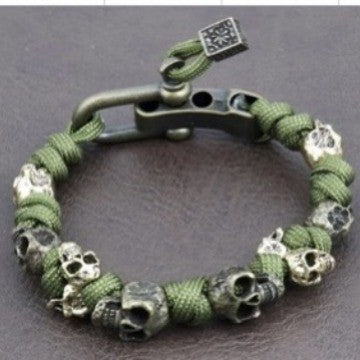 Green paracord bracelet with skull beads on a dark background