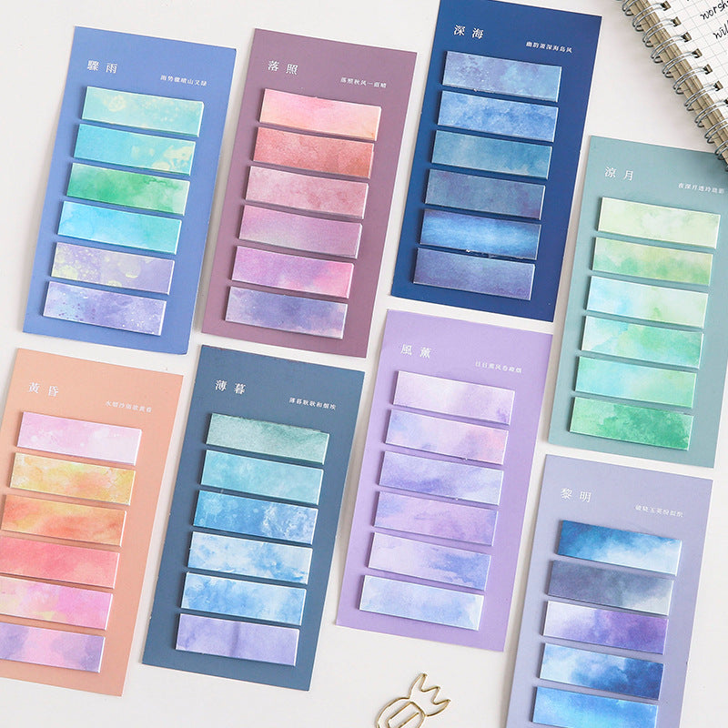 Set of colorful sticky notes with watercolor design on a white surface.