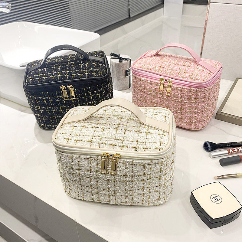 Three woven cosmetic bags in black, pink, and white on a bathroom counter with makeup items.