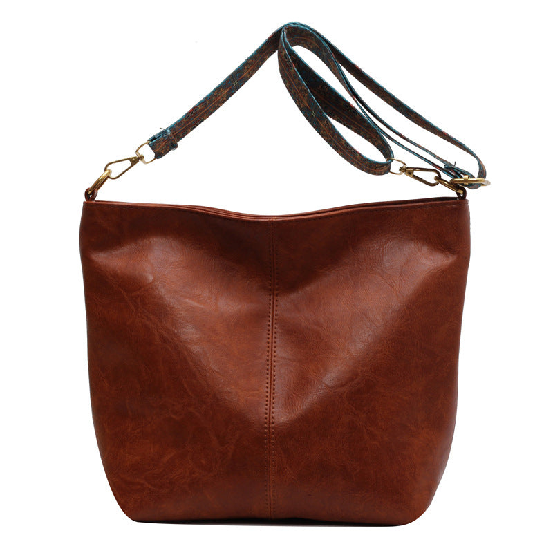 Brown leather handbag with a strap on a white background
