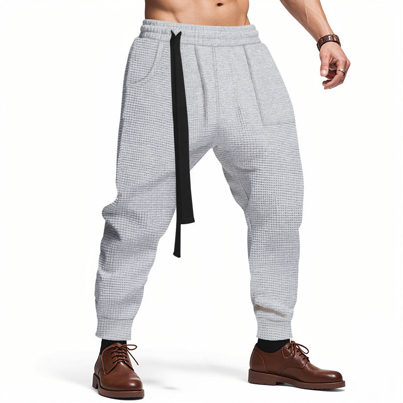 Gray checkered pants with a black strap worn by a person on a white background