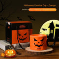 Halloween-themed cup with pumpkin design, gift box, and decorative elements on a wooden surface.