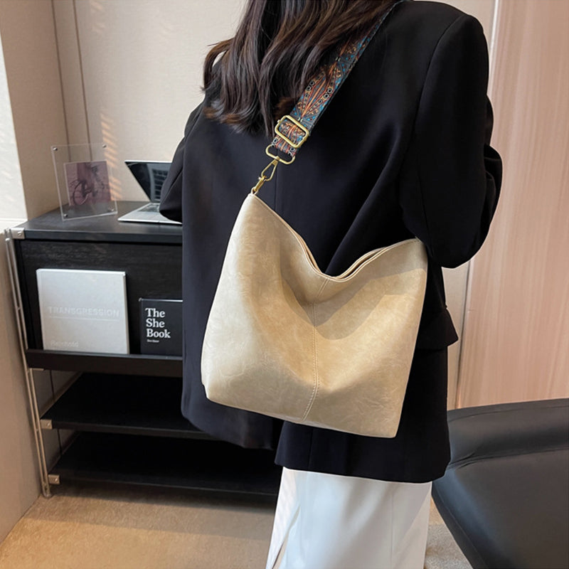 Person wearing a beige handbag in an indoor setting
