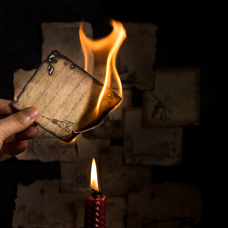 Hand holding a burning piece of paper with text and illustrations, surrounded by other similar papers.