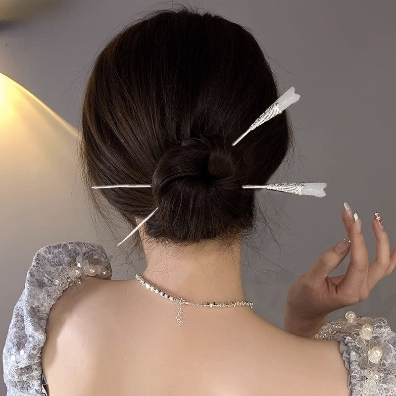 Person with decorative hairpins in their bun against a neutral background