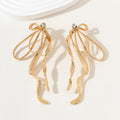 Gold earrings with a bow design on a light background