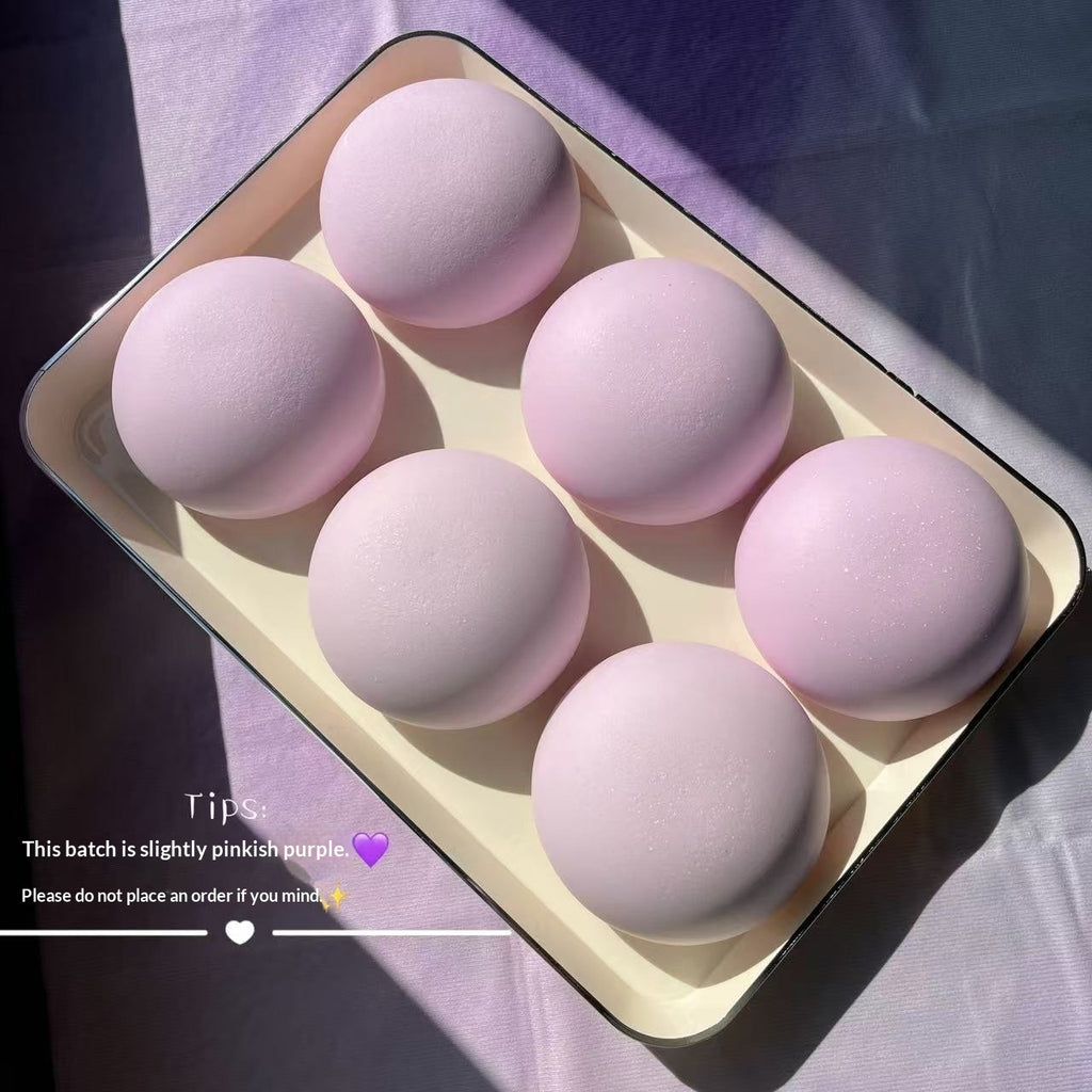 Set of pink makeup sponges in a tray on a purple fabric background
