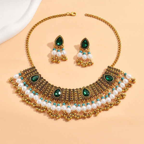 Gold necklace with green and white stones on a beige background