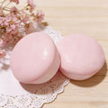 Two pink yogurt squishy on a wooden surface with delicate flowers in the background