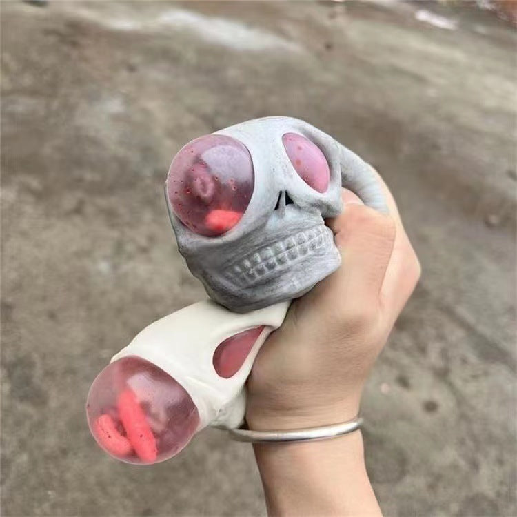 Hand holding a gray and pink toy resembling a skull fidget toy squishy stress relief with a blurred background