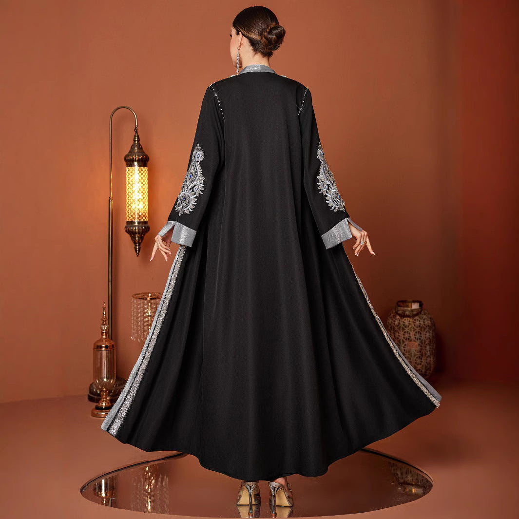 Woman wearing a black embroidered dress in a warm-toned room.